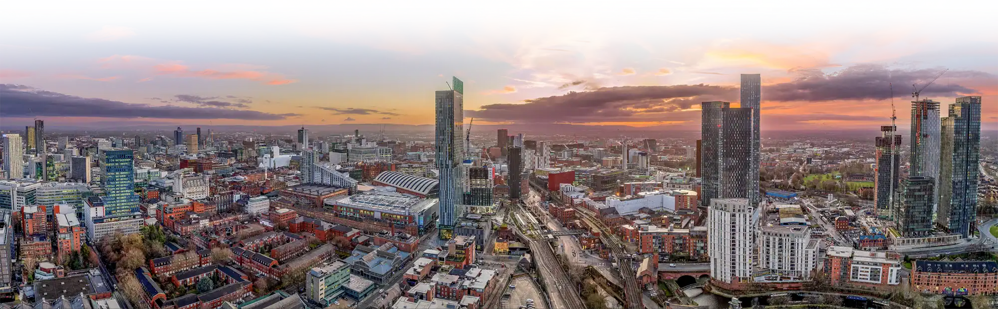 Aerial view of a cityscape at sunset, featuring modern skyscrapers and commercial buildings along a river—an inspiring vision of Manchester 2025, perfect for a Training Demo Day in a thriving urban environment. - Ribble Marine